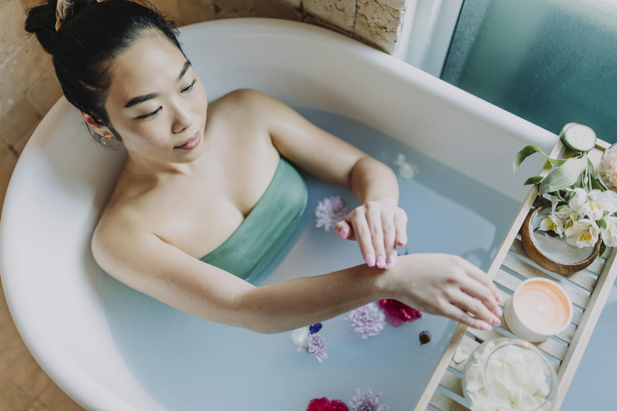 A woman enjoys a calming bath with flowers and candles, embodying self-care and relaxation.