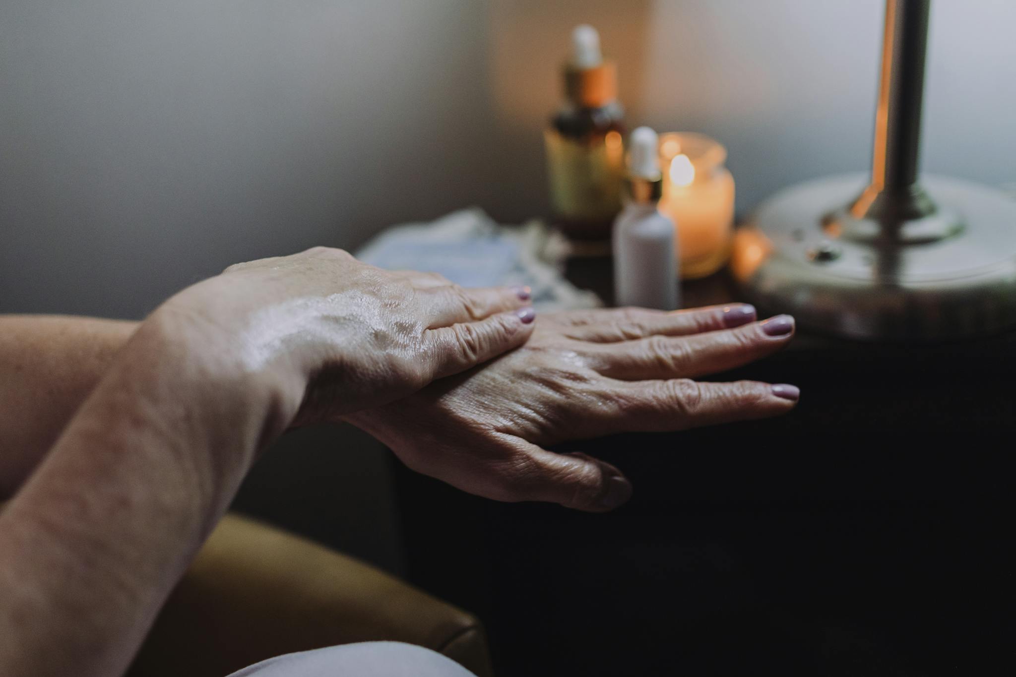 Hand care with lotion in a soothing spa ambiance, featuring candles and relaxation elements.