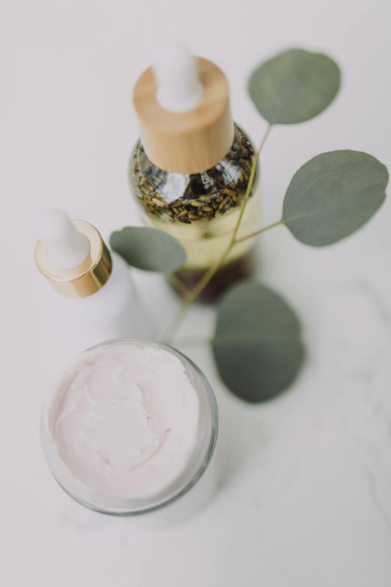 Minimalist skincare display featuring creams and oils with eucalyptus leaves.