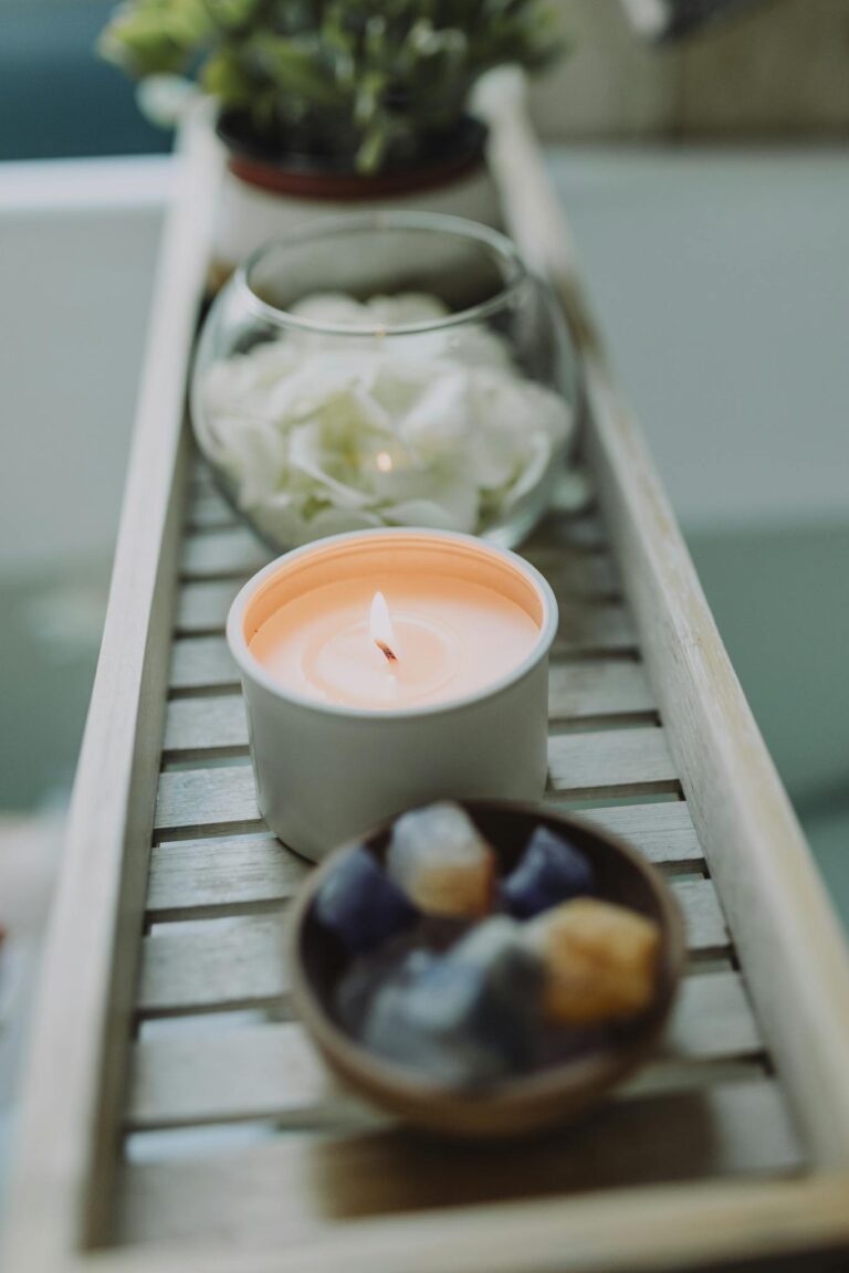 Peaceful spa setup with lit candle and healing crystals on a wooden tray.